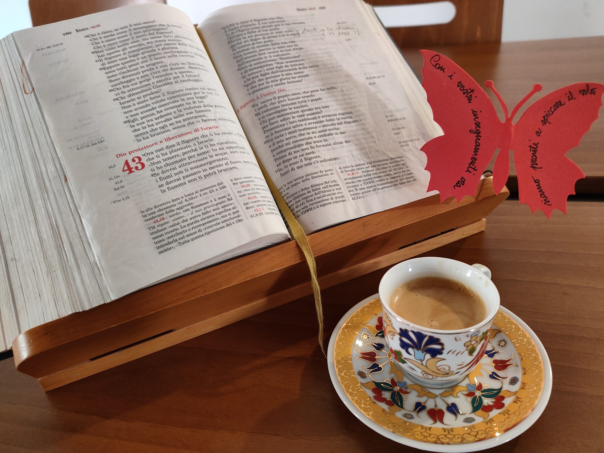Bibbia aperta su un leggio accanto a una tazza di caffè